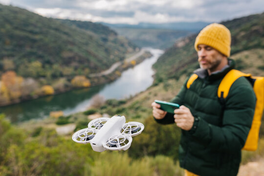 Man flying drone over scenic river landscape