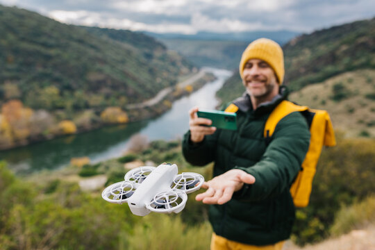 Man controlling drone over scenic landscape