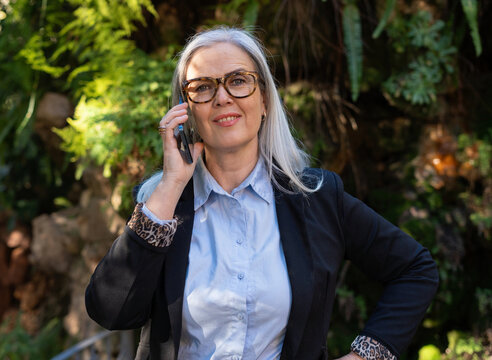 A confident professional woman is engaged in a conversation while talking on her phone outdoors
