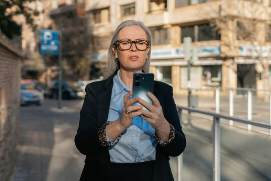 A confident business woman is seen in an urban environment using her smartphone effectively