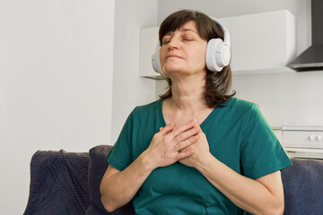 Adult woman finding peace meditating at home with eyes closed and hands on chest