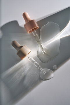 Skincare product droppers with clear liquid serum spills