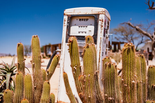Deserted gas pump among cacti in barren landscape