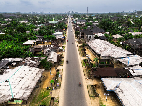 Aerial view of a long road cutting through the heart of the town, bordered by buildings and lush greenery, Gokana, Rivers, Nigeria.