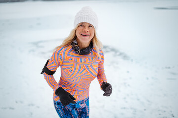 Fototapeta premium Active elderly woman jogging in cold snowy weather.