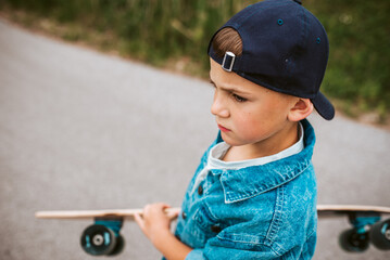 Young boy learning to ride longboard on street.