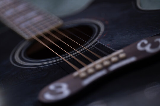Close-up detail of acoustic guitar strings, showing metal texture and warm wooden tones. Musical instrument background with shallow depth of field - Powered by Adobe