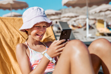 Gril relaxing on beach lounger with smartphone in hand.