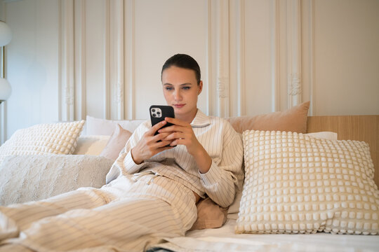 Young woman relaxing at home using mobile phone