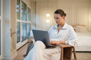 Young woman working on a laptop at home in cozy ambiance