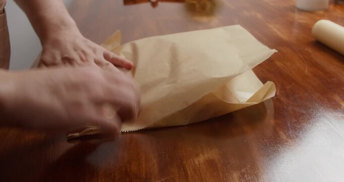 Woman wraps salmon fillet seasoned with salt and pepper in parchment paper for curing. Close-up of homemade salmon preparation process in kitchen, traditional food preservation and cooking at home.