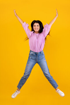 Euphoria concept. Full length portrait on positive armenian woman jumping and fooling isolated on yellow studio background, crop. Excited female celebrating win