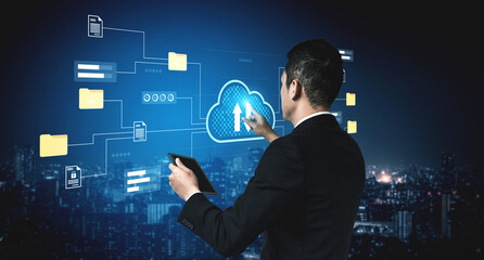 A businessman in a suit uses a tablet to interact with a digital cloud interface, showcasing data uploading and analytics in a vibrant cityscape at night. Gantry