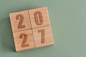 Wooden cubes with year 2027 on green background, New Year concept.