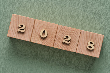 Wooden cubes with numbers 2028 on green background, New Year concept.