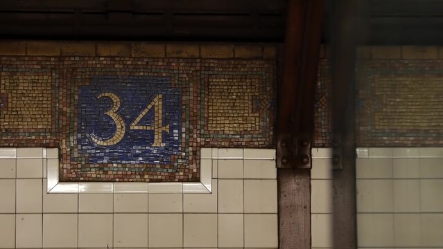 New York City Manhattan Midtown subway platform, 34 street metro near Herald Square and Penn Station, United States railway. Public metropolitan transport in USA, american railroad. Sign on wall, tile