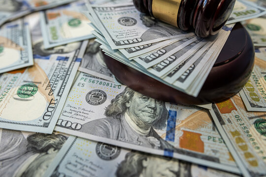 Judge gavel on dollar bills representing justice and financial decision