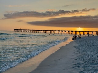 Pensacola pier orange sunset with ocean and white beach sand