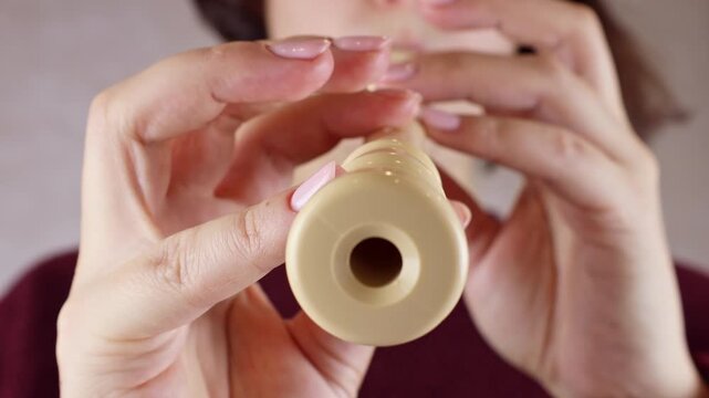 Woman holding in her hands and playing block flute (recorder) musical instrument