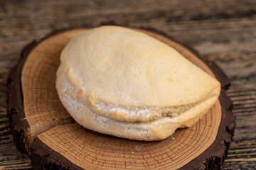 a whole fresh shortbread bun with cottage cheese filling on a wooden board on the table, soft pastries stuffed with cottage cheese and sugar are on the board