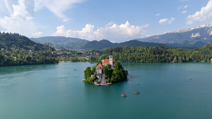 Aerial drone view of Bled Island with the Church of the Assumption in the middle of Lake Bled, Slovenia. The iconic island church is surrounded by turquoise alpine waters and forested mountains. Famou