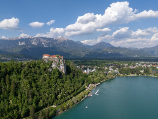 Aerial view of Bled Castle overlooking Lake Bled, Slovenia. Medieval fortress on a cliff captured by drone, surrounded by alpine landscape and clear blue water. Famous European travel destination and 