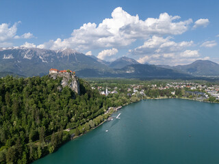 Aerial view of Bled Castle overlooking Lake Bled, Slovenia. Medieval fortress on a cliff captured by drone, surrounded by alpine landscape and clear blue water. Famous European travel destination and 