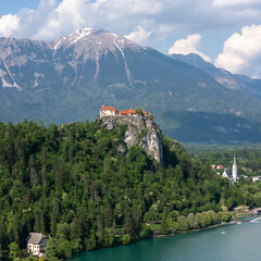 Aerial view of Bled Castle overlooking Lake Bled, Slovenia. Medieval fortress on a cliff captured by drone, surrounded by alpine landscape and clear blue water. Famous European travel destination and 