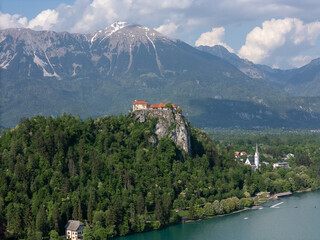 Aerial view of Bled Castle overlooking Lake Bled, Slovenia. Medieval fortress on a cliff captured by drone, surrounded by alpine landscape and clear blue water. Famous European travel destination and 