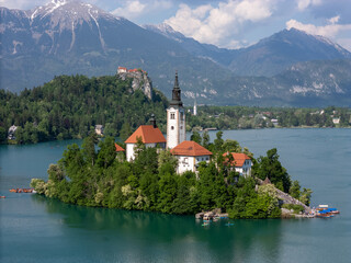 Aerial drone view of Bled Island with the Church of the Assumption in the middle of Lake Bled, Slovenia. The iconic island church is surrounded by turquoise alpine waters and forested mountains. Famou