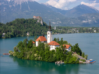 Aerial drone view of Bled Island with the Church of the Assumption in the middle of Lake Bled, Slovenia. The iconic island church is surrounded by turquoise alpine waters and forested mountains. Famou