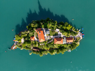 Aerial drone view of Bled Island with the Church of the Assumption in the middle of Lake Bled, Slovenia. The iconic island church is surrounded by turquoise alpine waters and forested mountains. Famou