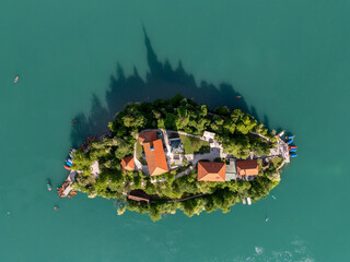 Aerial drone view of Bled Island with the Church of the Assumption in the middle of Lake Bled, Slovenia. The iconic island church is surrounded by turquoise alpine waters and forested mountains. Famou