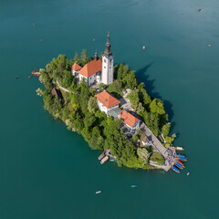 Aerial drone view of Bled Island with the Church of the Assumption in the middle of Lake Bled, Slovenia. The iconic island church is surrounded by turquoise alpine waters and forested mountains. Famou