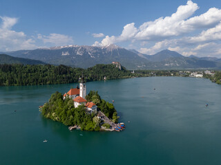Aerial drone view of Bled Island with the Church of the Assumption in the middle of Lake Bled, Slovenia. The iconic island church is surrounded by turquoise alpine waters and forested mountains. Famou