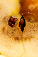 a cut yellow apple with a large orange spot during rotting, one apple on a black wooden table made...