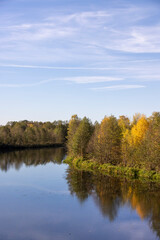 Fototapeta premium autumn river in sunny weather , beautiful deciduous trees on the riverbank before the fall of leaves, evening time before sunset