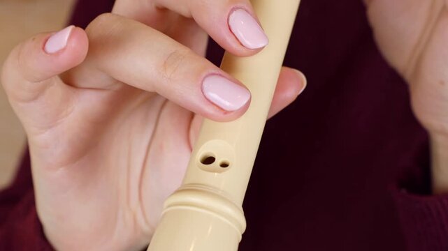 Woman holding in her hands and playing block flute (recorder) musical instrument