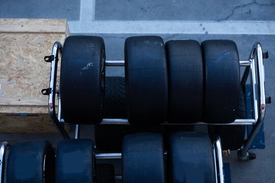 Mechanic performs automotive maintenance on red race car wheel and tire. focused pit stop service requiring precision for high speed vehicle performance and competition