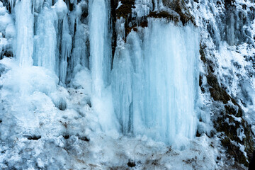 Icefall formation at Rudawka Rymanowska, featuring shimmering blue icicles cascading down a river cliff in the winter landscape, showcasing natures beauty and cold climate.