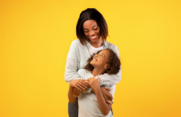 Mother's love and care. Happy young african american mom embracing her cute little daughter from...