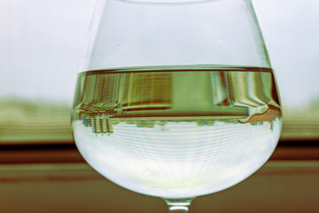 Clear glass of water or white wine on a table near window. Refreshing drink close up with...