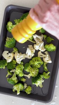 Seasoning a Sheet Pan of Broccoli and Cauliflower Vegetable Shot from Above