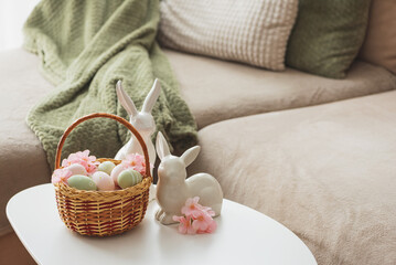 Easter Basket with Ester Eggs,  Plush Bunny and Spring Decor on White Table intoCozy Living Room