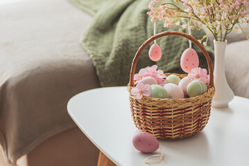 Easter Basket with Ester Eggs,  Plush Bunny and Spring Decor on White Table intoCozy Living Room