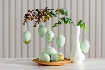 Hanging Easter Eggs and Spring Branches in Vase. Festive Pastel Decor