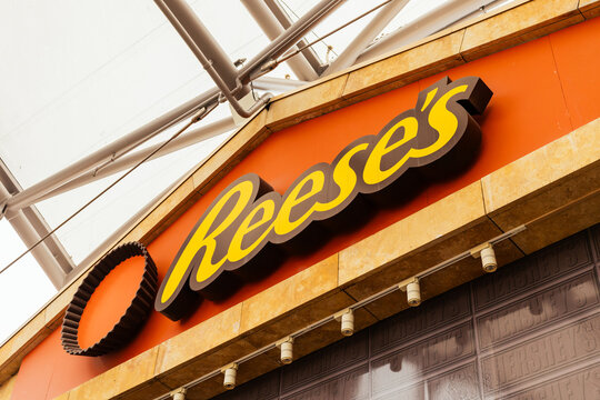 Singapore - January 7, 2026: A brightly colored sign displays the logo of a well-known chocolate and peanut butter brand outside a store, Reese's. The location is lively with shoppers walking by