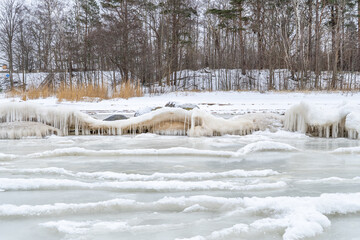 Frozen Forest Lakeshore with Layered Drift Ice and Icicle-Covered Rocks, Quiet Winter Landscape Conveying Silence, Cold Stillness and a Calm, Remote Northern Mood © Edijs
