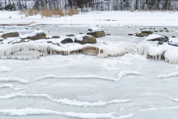 Frozen Lakeshore with Icicle-Covered Rocks and Layered Drift Ice, Quiet Winter Landscape Conveying Cold Stillness, Silence and a Remote Northern Mood © Edijs