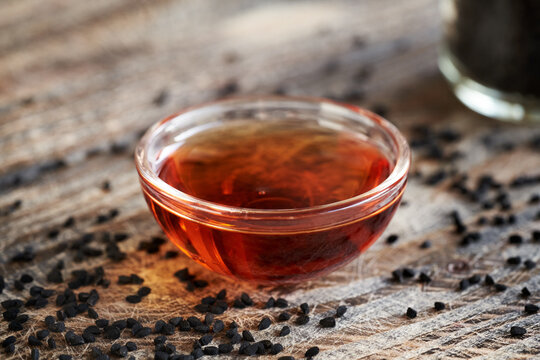 Nigella or black cumin seed oil in a glass bowl Healthy anti-inflammatory and antioxidant supplement.